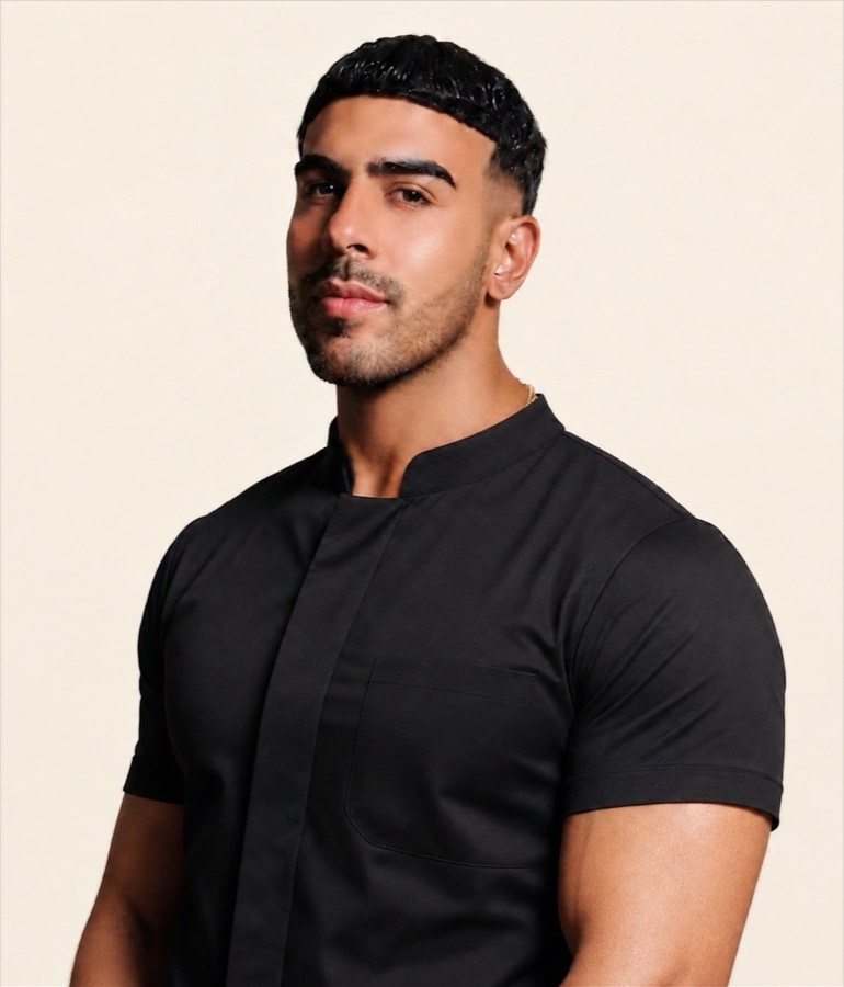 Kem Ibrahim, massage therapist, in a black tunic against a warm cream background